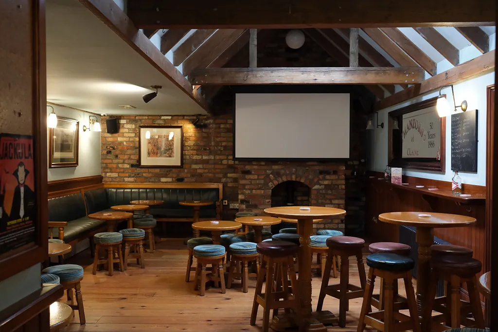 The Backroom: exposed timber beams, a red-brick hearth, high tables and a large screen