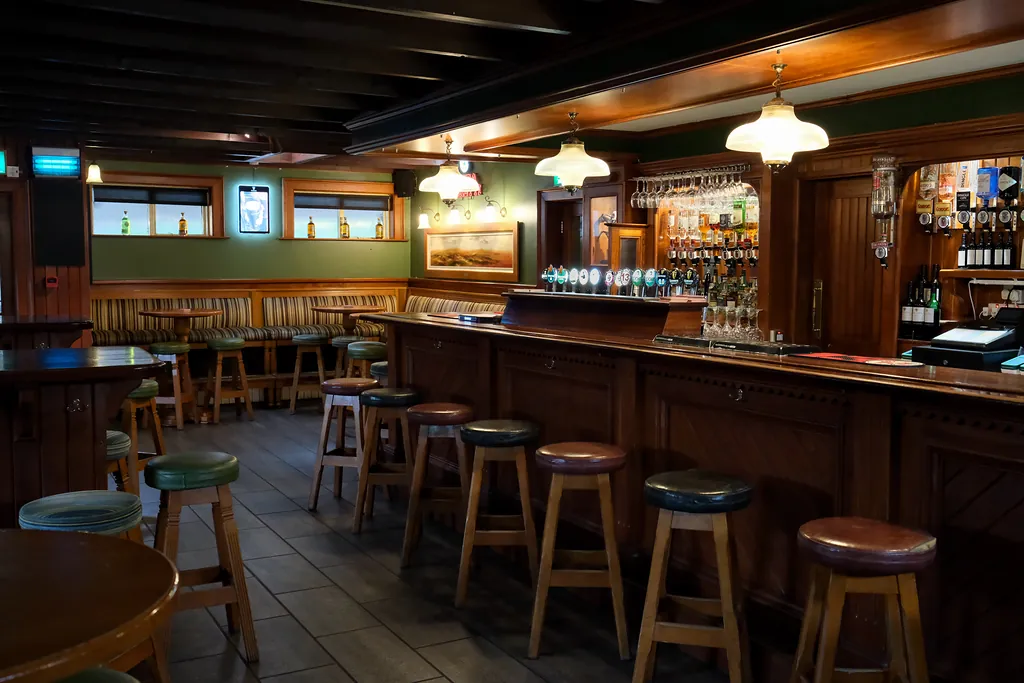 The main bar: a long wooden counter lined with cushioned stools under glass pendant lamps