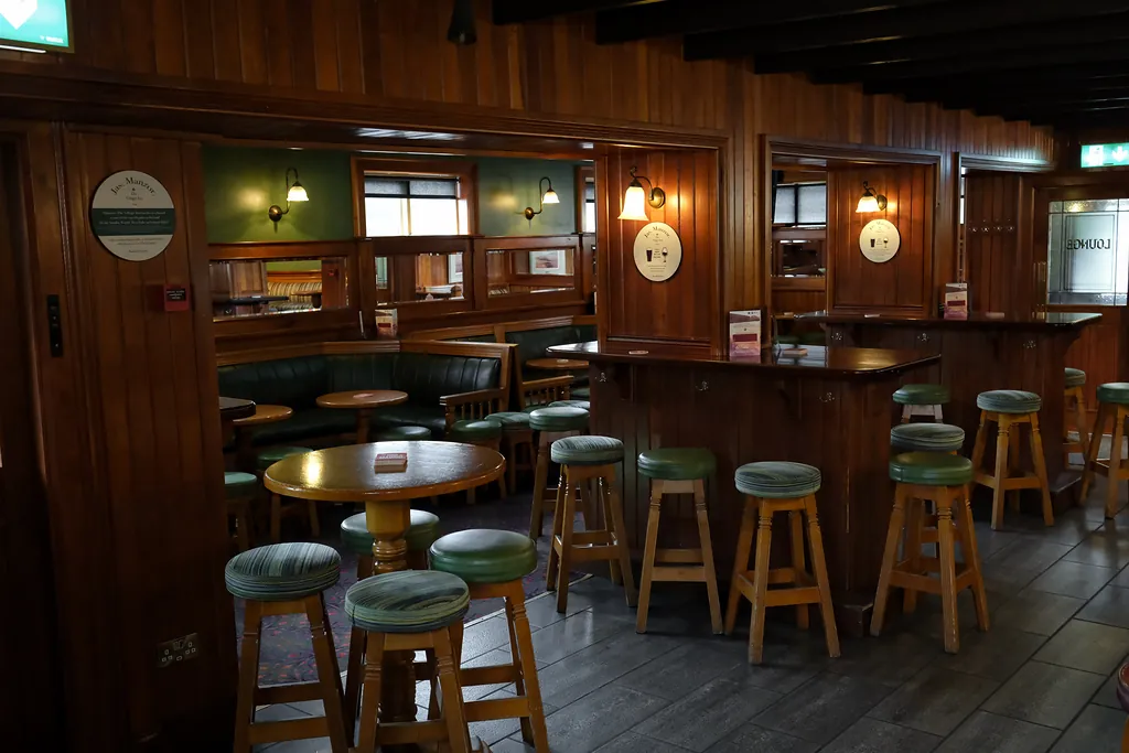 The Lounge: green banquettes, round tables and wood-panelled walls lit by wall lamps